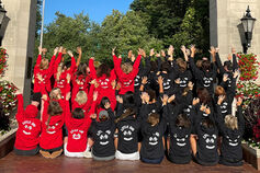 Students with IUSF sweatshirts sit in front of Sample Gates.